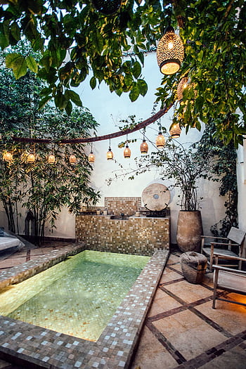 Tranquil courtyard pool with lush greenery and Moroccan lanterns. HD phone wallpaper