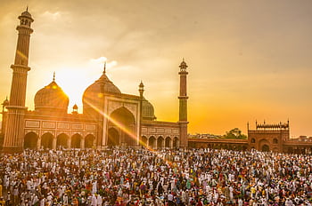Vibrant scene of a large crowd gathered for Ramadan prayers at Jama Masjid during a stunning sunset. HD wallpaper