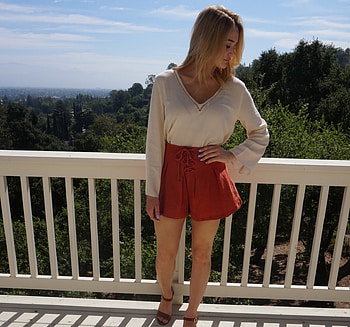 Hunter H King, scenic overlook, tie front, standing by white fence, blonde, white top, blue painted finger nails, red shorts, v shaped neck line HD wallpaper