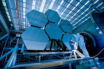 Engineers in protective suits work on telescopic mirrors in a high-tech lab. HD wallpaper