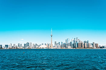 Beautiful view of Toronto skyline featuring the iconic CN Tower and vibrant blue waterfront. HD wallpaper