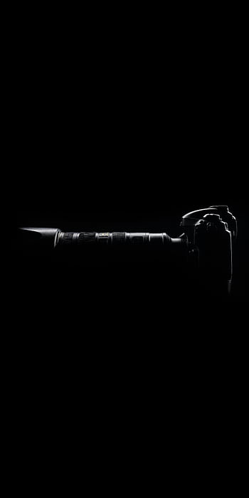 Silhouette of a modern camera with lens against a dark black backdrop. HD phone wallpaper
