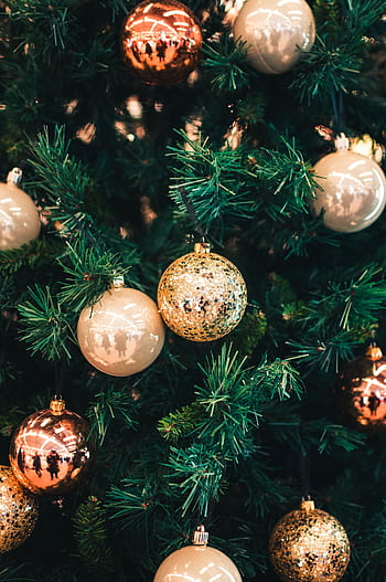 Festive holiday ornaments including gold and copper colors adorning a Christmas tree. HD phone wallpaper