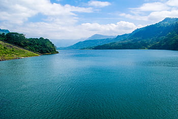 Idyllic lake landscape with lush green mountains and clear blue sky. HD wallpaper