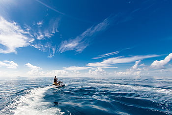A thrilling jet ski ride on the open ocean beneath bright blue skies, perfect for adventure seekers. HD wallpaper