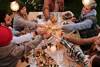 Group of friends toasting with glasses at an outdoor dinner table. Lively and joyful atmosphere. HD wallpaper