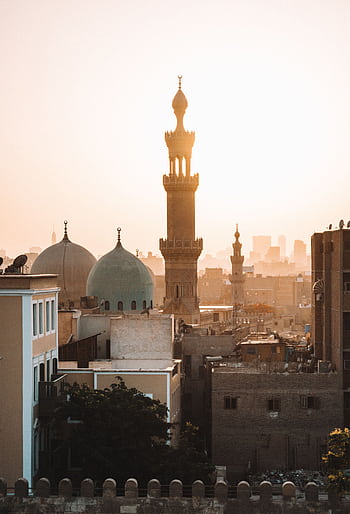 A stunning view of mosque minarets at sunset in Cairo, highlighting cultural architecture. HD phone wallpaper