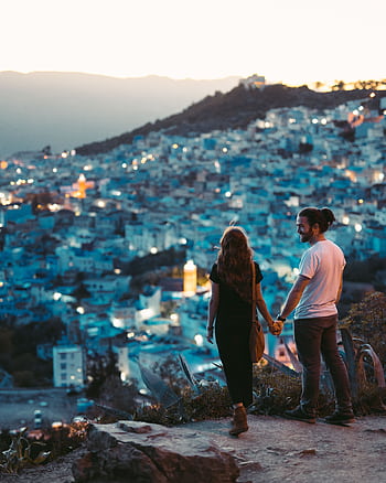 A romantic couple holding hands with a view of Chefchaouen, Morocco at twilight. HD phone wallpaper