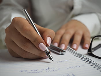 A detailed of handwriting in a notebook with a fountain pen and glasses, ideal for office themes. HD wallpaper