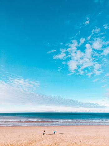 Tranquil scene of a lone walker on Colwyn Bay beach under a vast blue sky. HD phone wallpaper