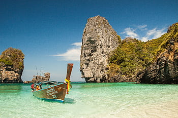 A que tropical beach with a traditional boat and stunning limestone cliffs in clear turquoise waters. HD wallpaper