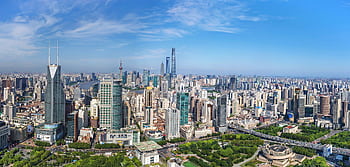 A stunning aerial view of Shanghai's modern skyline with iconic skyscrapers under a clear blue sky. HD wallpaper