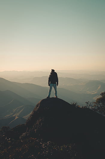 A man enjoys a breathtaking view from a mountain peak, embracing dom and adventure. HD phone wallpaper