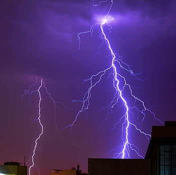 A striking capturing a powerful lightning bolt illuminating the city skyline at night. HD wallpaper