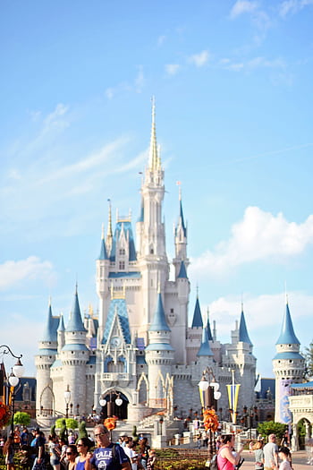 Bright daytime view of the famous Disney castle with a lively crowd in Orlando. HD phone wallpaper