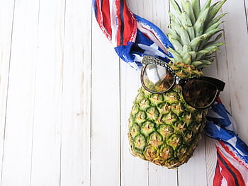 Stylish pineapple wearing sunglasses with a colorful scarf on a wooden background. HD wallpaper