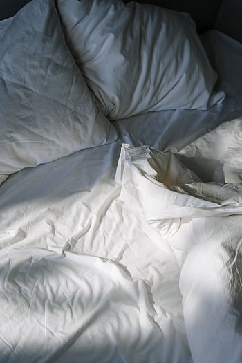 A cozy, inviting bed with white linens lit by morning sunlight, creating a restful atmosphere. HD phone wallpaper