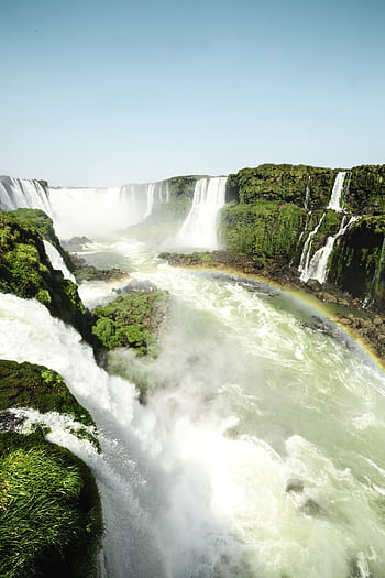 Scenic view of Iguazu Falls cascading with vibrant rainbow and lush greenery. HD phone wallpaper
