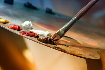 Vibrant artist palette with paint and brush creating colorful artwork. HD wallpaper