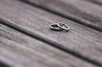 Elegant two-tone wedding rings on rustic wooden surface, symbolizing love and unity. HD wallpaper