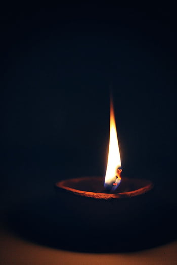 A close-up capture of a candle's flame illuminating the dark ambiance, creating a peaceful mood. HD phone wallpaper