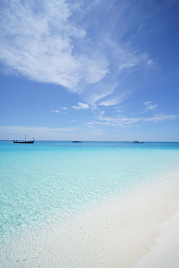 Peaceful beach scene with crystal clear waters and a deep blue sky, ideal for travel inspiration. HD phone wallpaper