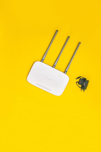 White router with three antennas and cables on bold yellow background, ideal for tech concepts. HD phone wallpaper
