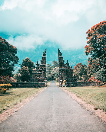 Majestic Balinese gate amidst a lush, tropical landscape and towering mountains, under a bright sky. HD phone wallpaper