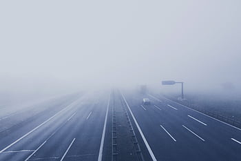A fog-covered highway with vehicles disappearing into the mist, creating a mysterious and tranquil scene. HD wallpaper