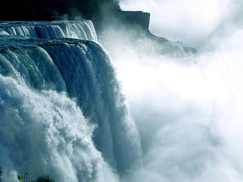 Dramatic waterfall cascading amid mist, capturing the power of nature in daylight. HD wallpaper