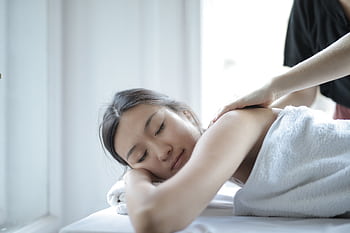 Asian woman enjoying a relaxing body massage at a spa to unwind and rejuvenate. HD wallpaper