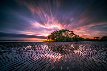 Vibrant sunset over a tropical beach with rippling sand and reflective water. HD wallpaper