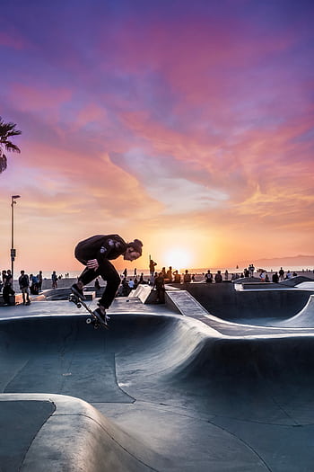 Dynamic shot of a skateboarder in action at Venice Beach Skatepark during sunset. HD phone wallpaper