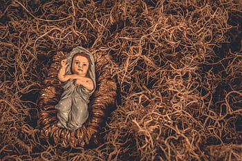 A nativity scene featuring a baby Jesus figurine surrounded by straw, symbolizing hope and tradition. HD wallpaper