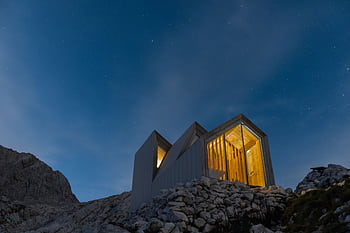 Contemporary cabin illuminated against a starry night in Slovenia's mountains. HD wallpaper