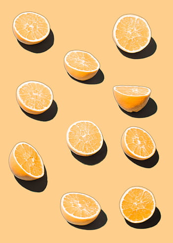Sliced citrus fruits arranged on a warm yellow backdrop, casting soft shadows. HD phone wallpaper