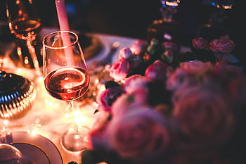 Romantic evening setup featuring rose wine and candlelight, perfect for celebrations. HD wallpaper