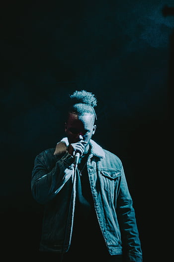 Dramatic of a rapper performing under spotlight, wearing a stylish jacket, highlighting hip-hop culture. HD phone wallpaper