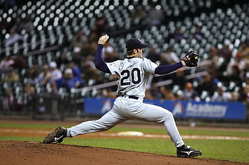 Baseball player pitching on field during a game, showcasing athletic action and focus. HD wallpaper