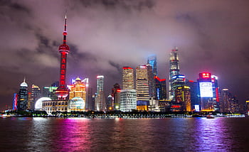 Captivating view of Shanghai's illuminated skyline reflecting on the waterfront at night. HD wallpaper