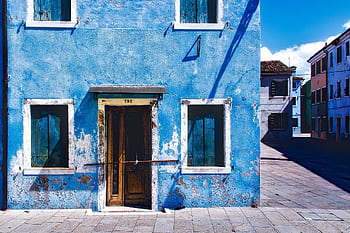 An old, rustic blue building with wooden windows captured in bright daylight on an empty street. HD wallpaper