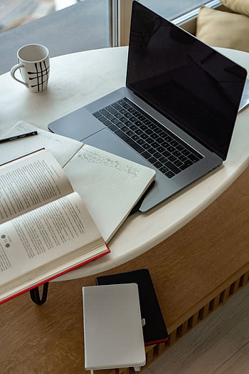 A cozy indoor workspace featuring a laptop, open book, notepad, and coffee, perfect for studying or remote work. HD phone wallpaper