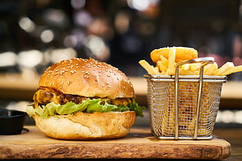 A delicious cheeseburger with crispy french fries served on a wooden platter, perfect for lunch or dinner. HD wallpaper