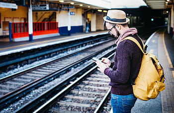 Man with backpack uses at urban train station platform. HD wallpaper