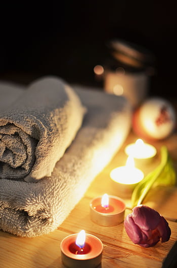 Relaxing spa atmosphere with candles, towels, and a tulip, perfect for wellness and self-care. HD phone wallpaper