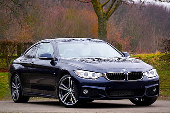 Stylish blue luxury coupe parked outdoors in autumn landscape, showcasing elegance and design. HD wallpaper