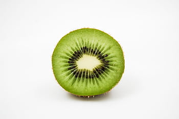 Close-up of a fresh kiwi fruit slice showcasing its vibrant green and black seeds. HD wallpaper