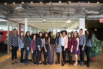 A diverse group of women in technology poses together in an office lobby, exuding confidence and teamwork. HD wallpaper