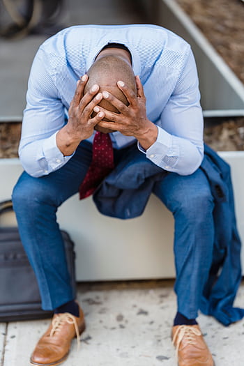 A businessman in a suit sits outdoors, head in hands, expressing stress and despair. HD phone wallpaper