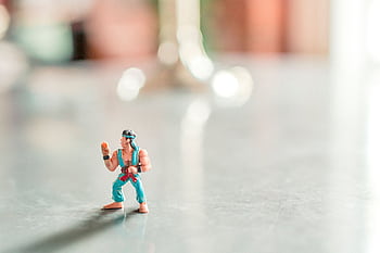 Close-up of a colorful action figure posed on a shiny surface with a blurred background. HD wallpaper